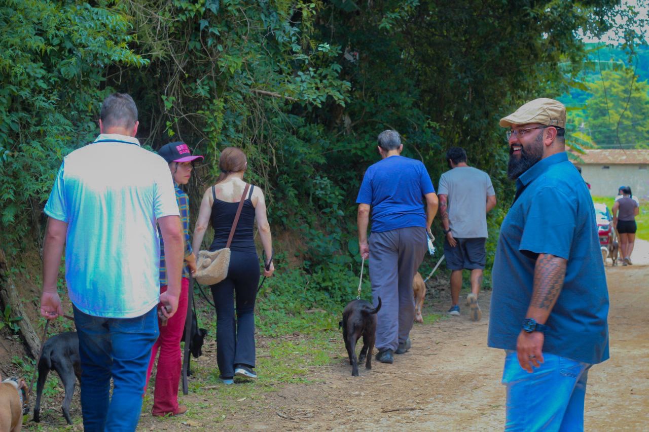 Grupo de donos e cães caminhando em trilha durante passeio do Método MACAN